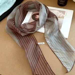 Elegant striped mesh scarf detail with brown and blue patterns on a brown base.