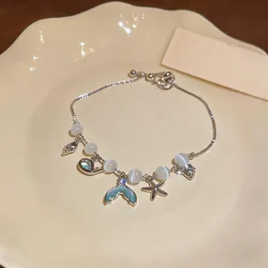 Close-up of elegant mermaid tail and starfish charms on cat-eye stone bracelet