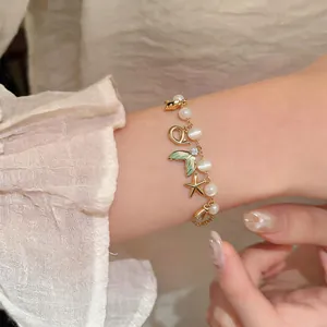 Close-up of ocean-themed bracelet with cat's eye stones and mermaid tail charm