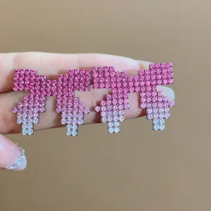 Detail view of pixelated bow earrings with pink ombre rhinestones on silver needles