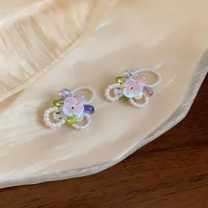 Macro view of sweet style iridescent flower earrings with pearly beads and crystals