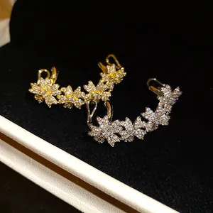 Close-up detail of sparkling zircon flower ear cuffs in gold and silver finish