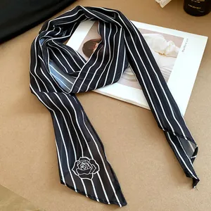 Detailed view of a black and white striped mesh neck scarf featuring a white rose print.