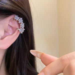 Detailed view of 14k gold plated zirconia flower ear cuff earring worn on an ear.