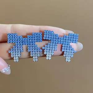 Detailed macro shot of pixelated bow earrings featuring a blue gradient rhinestone finish