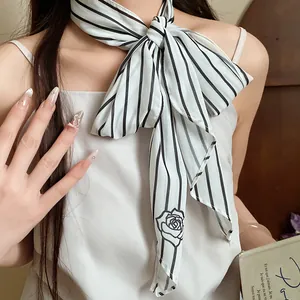 Elegant detail of a striped mesh scarf necklace with a rose pattern worn by a model
