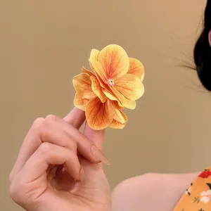 Primo piano di un fermaglio per capelli a fiore giallo con petali in tessuto realistici