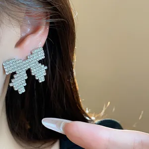 Close-up detail of a silver bow stud earring encrusted with sparkling rhinestones