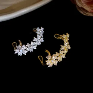 Detailed view of 14k gold-plated zircon flower ear cuffs on a black background.