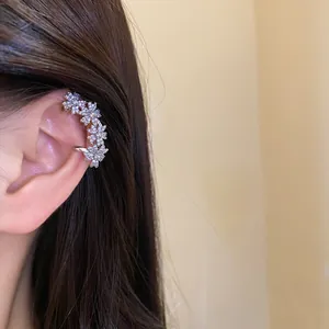Detail view of a sparkling zircon flower ear cuff worn on the upper ear cartilage.