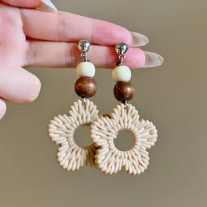 Detailed view of handmade bohemian rattan flower earrings with decorative wooden beads.