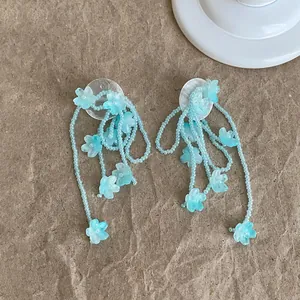 Nahaufnahme von blauen Perlenblumen-Quastenohrringen mit feinen Blütendetails