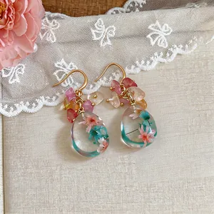 Macro view of clear resin earrings featuring delicate flowers and colorful beads