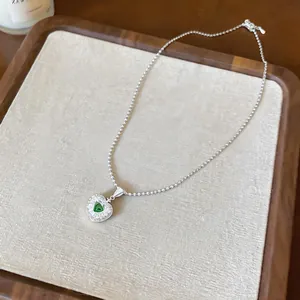 Detail shot of elegant apple-shaped pendant with green zircon on a textured display