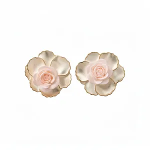 Élégantes boucles d'oreilles rose en résine avec pétales dorés sur fond blanc neutre