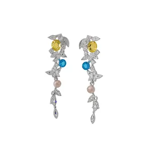 Boucles d'oreilles pendantes feuilles élégantes avec zircons bleus et jaunes sur fond blanc