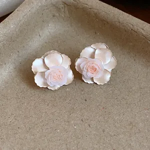 Gros plan de boucles d'oreilles fleurs en résine avec des pétales roses délicats