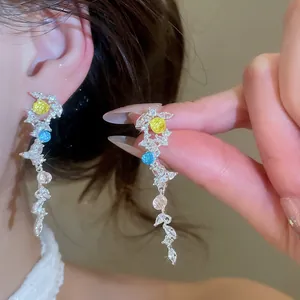 Gros plan de boucles d'oreilles pendantes feuilles avec zircons colorés scintillants.