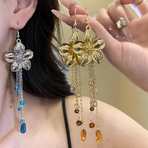 Dettaglio di eleganti orecchini a fiore in oro e argento con lunghe nappe di cristallo