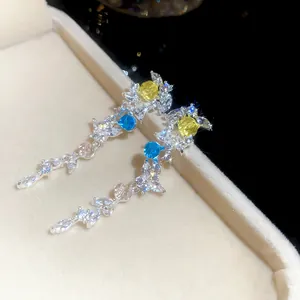 Gros plan de boucles d'oreilles élégantes en zircon en forme de feuille sur une boîte.