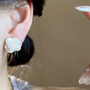 Vue détaillée d'une magnifique boucle d'oreille fleur en résine blanche à l'oreille