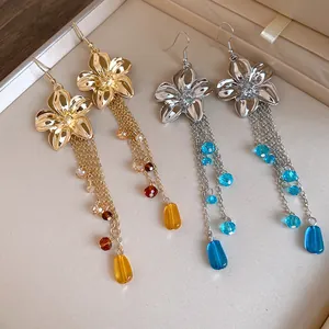 Primo piano di eleganti orecchini a fiore in oro e argento con nappe di cristallo.