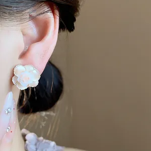 Gros plan de boucles d'oreilles fleurs en résine blanche, détail de bijoux floraux élégants.