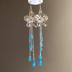 Dettaglio di orecchini a fiore in argento con lunghe catenelle di nappe in cristallo blu