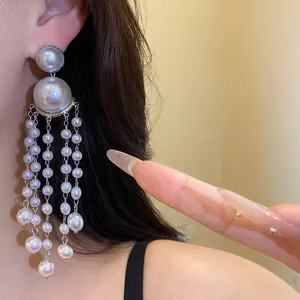 Close-up of elegant retro pearl tassel earrings worn on ear with silver finish