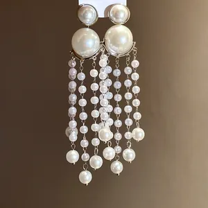Detailed macro view showing the elegant white pearl tassel earrings with vintage French style.