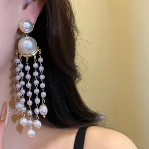 Close-up view of elegant French vintage style long pearl tassel earrings worn by a model