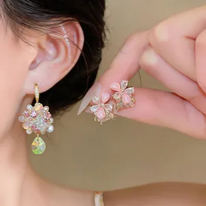 Close-up detail of sweet floral earrings featuring pastel pink and clear shimmering crystals.
