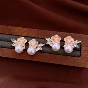 Macro detail of vintage pink flower stud earrings with elegant pearls and zircon leaves
