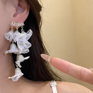Macro detail showing white chiffon flower tassels and sparkling zircon ear studs