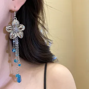 Eleganti orecchini a fiore in argento con cristalli blu su dettaglio della modella
