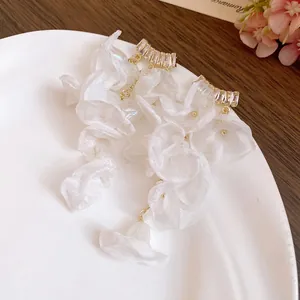 Close-up of elegant white chiffon flower tassel earrings with sparkling zircon studs