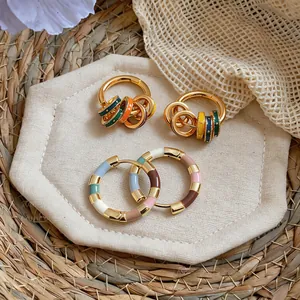 Detailed view of colorful enamel 14K gold plated hoop earrings on a neutral background