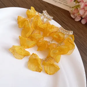 Detail view of yellow chiffon flower tassel earrings with sparkling zircon studs