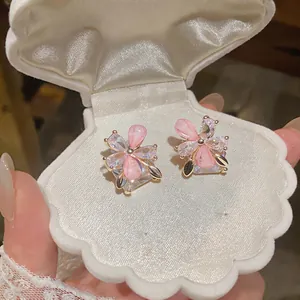 Close-up of pink flower stud earrings presented in a white shell-shaped jewelry box