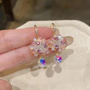 Close-up of colorful floral earrings with crystal beads and teardrop crystal pendants.