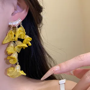 Detailed close-up of yellow chiffon flower tassel earrings with zircons worn on ear