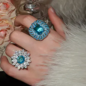 Macro view of blue zircon flower ring and square gemstone ring with intricate pavé