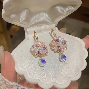 Close-up of colorful flower drop earrings with iridescent crystals in a shell box