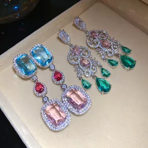 Close-up of sparkling zircon drop earrings with colorful gemstones in a jewelry box