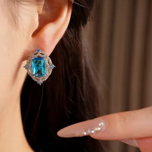 Close-up detail of an elegant blue zircon earring with silver setting on model's ear
