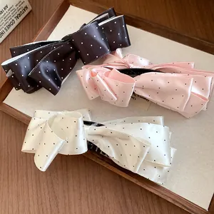 Gros plan de pinces à cheveux banane en satin à pois vintage en trois couleurs