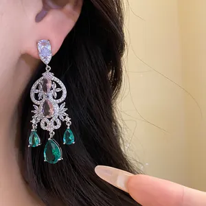 Elegant pear-shaped drop earrings with green and pink stones shown on model.