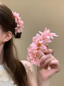 Dettaglio di forcina per capelli con fiori in tessuto rosa e gocce d'acqua per uno stile elegante.