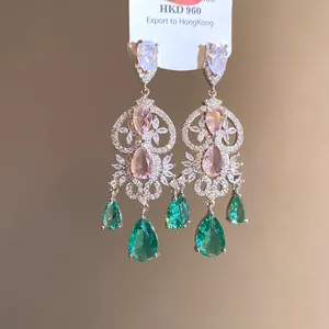 Macro view of vintage silver drop earrings with pink and green pear-shaped stones.