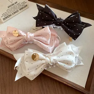 Gros plan détaillé de pinces à cheveux élégantes en satin à pois en noir, rose et blanc